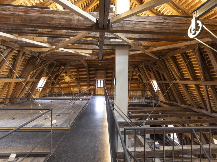 Dachstuhl des Cavazzen Lindau mit freiliegenden Holzbalken, modernen Stahlträgern und begehbarem Steg mit Geländer.
